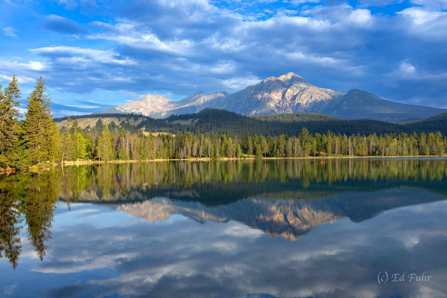 Pyramid Mountain reflects in the still sunrise waters of Edith Lake in Jasper National Park.