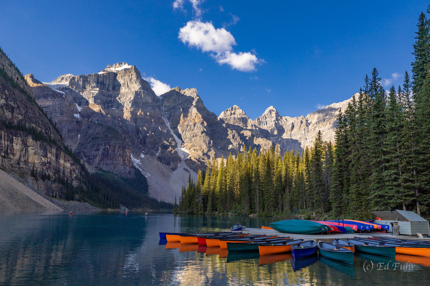 The warm light of late afternoon highlights the colorful canoes that are now tied up for the day on beautiful Lake Moraine.