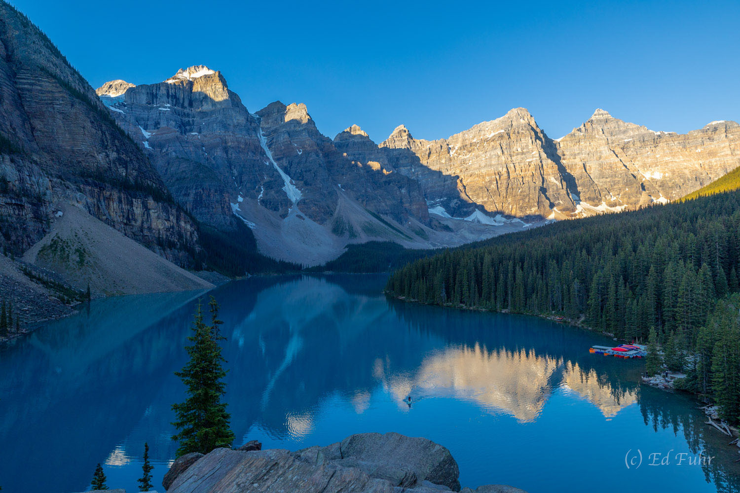 On the eastern shore of Moraine Lake, a tall pile of glacial rock is a popular place to witness sunrise as is it reaches the...