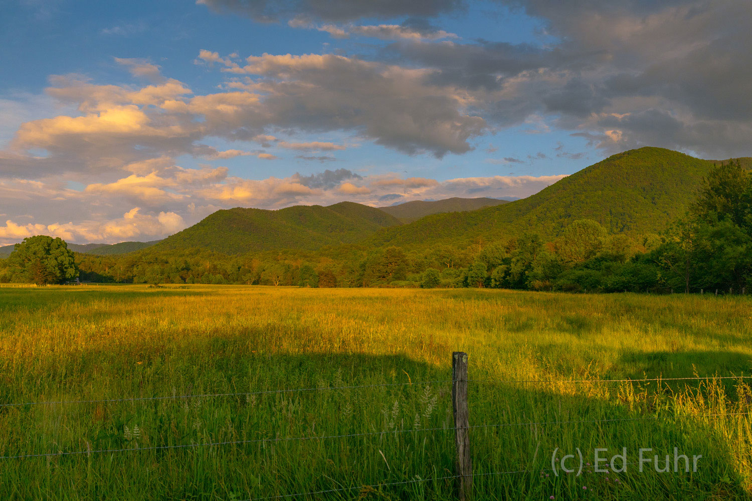 As the sun sets, Cades Cove and the surrounding mountains are bathed in a warm light.