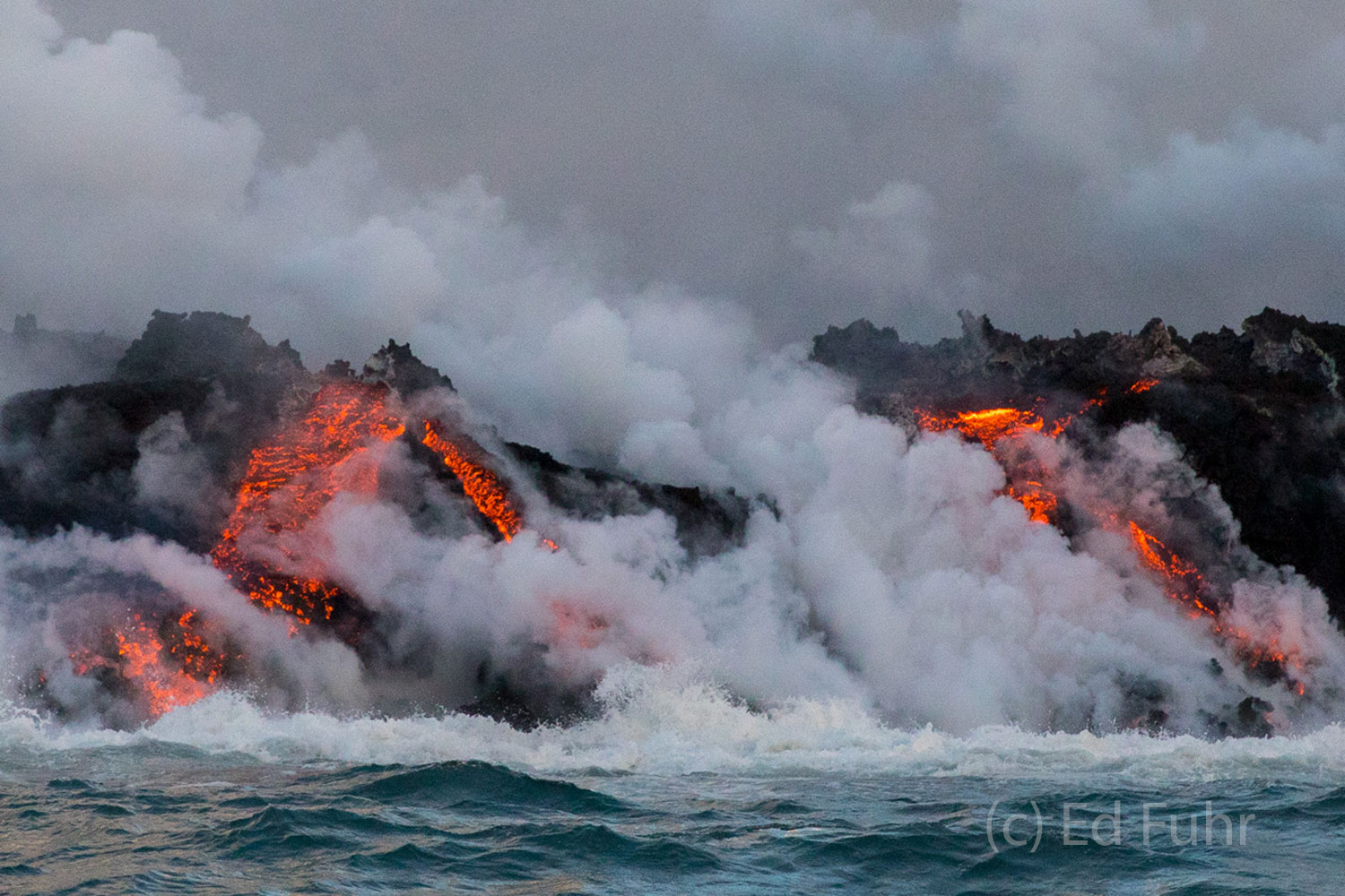 Hot steam rises from the molten lava as it enters the Pacific seas.