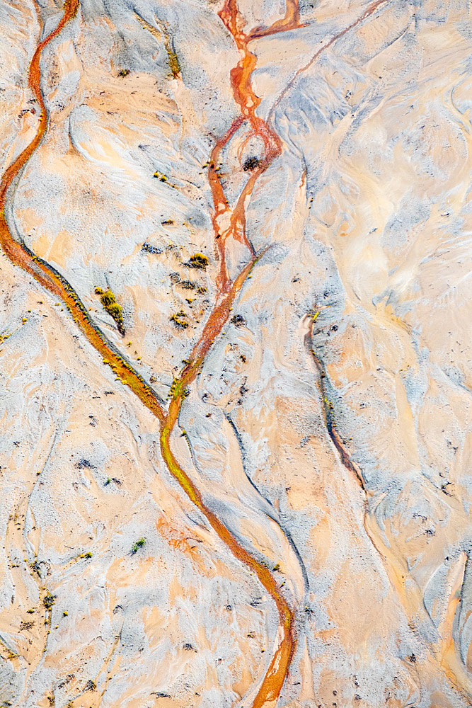 A red copper-colored stream twists and turns across this valley.
