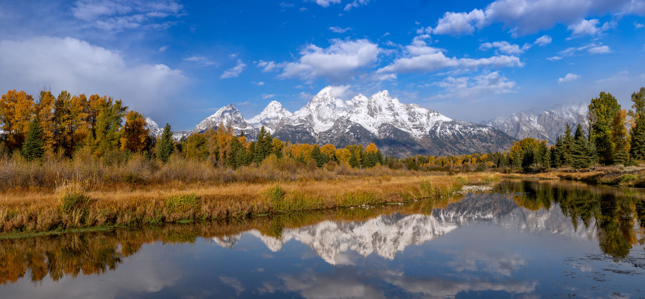 Freshly coated in a late fall snow, the Teton range and cottonwoods reflect in the still waters of this beaver pond near Schwabacher...