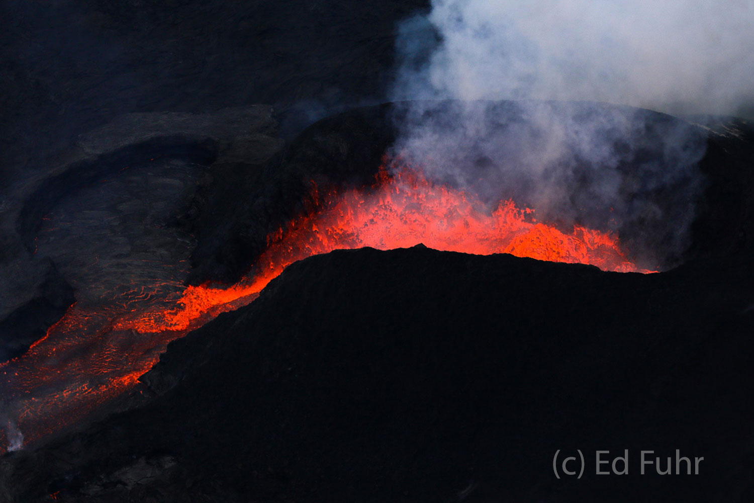 A cone hundreds of feet high has been built by the lava as it pours out and down the land.