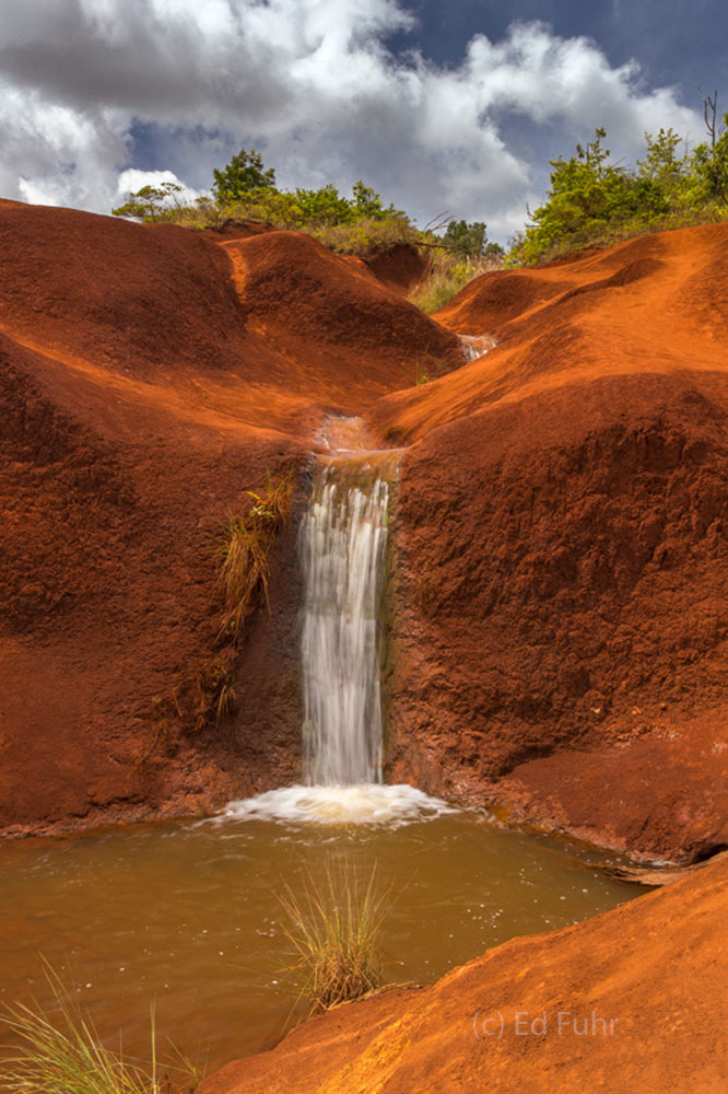 Carved into the red dirt hills that lead to Waimea Canyon, this seasonal waterfall seems transplanted from the desert southwest...