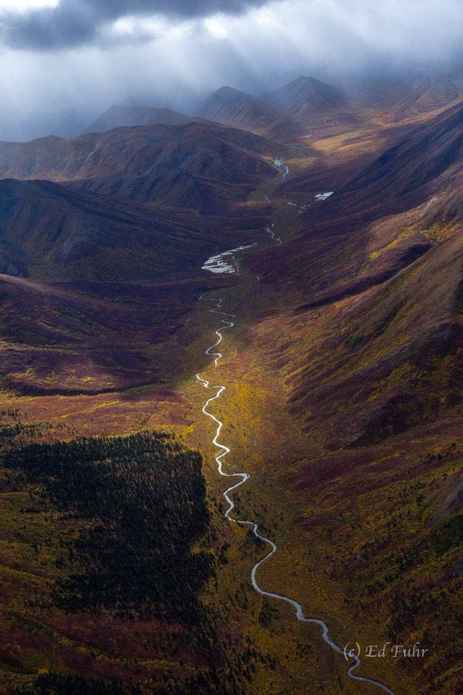 A river slices through this autumn valley.