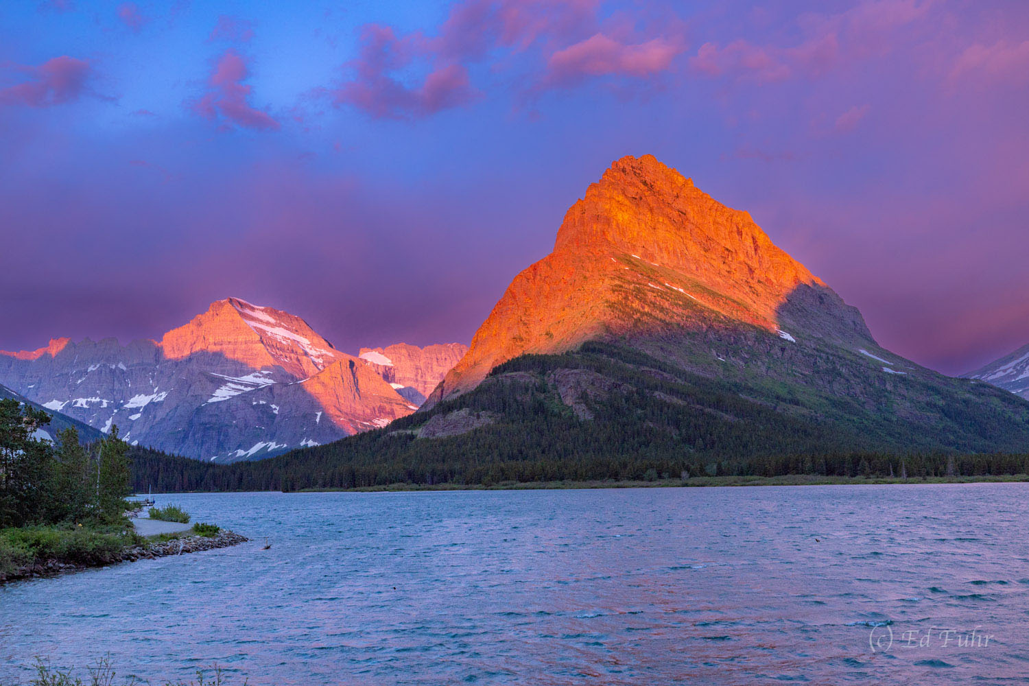 Grinnell Point glows at sunrise on the western shores of Swiftcurrent Lake across from Many Glacier Hotel.