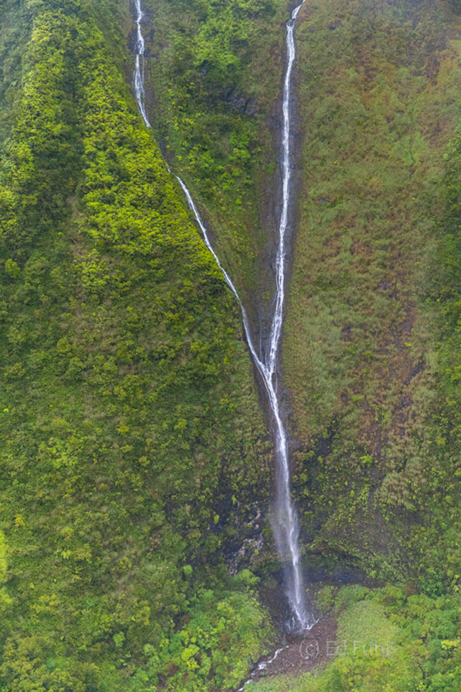 The cool air and mist of Kauai's mountains rush by as I lean out a no-door helicopter.