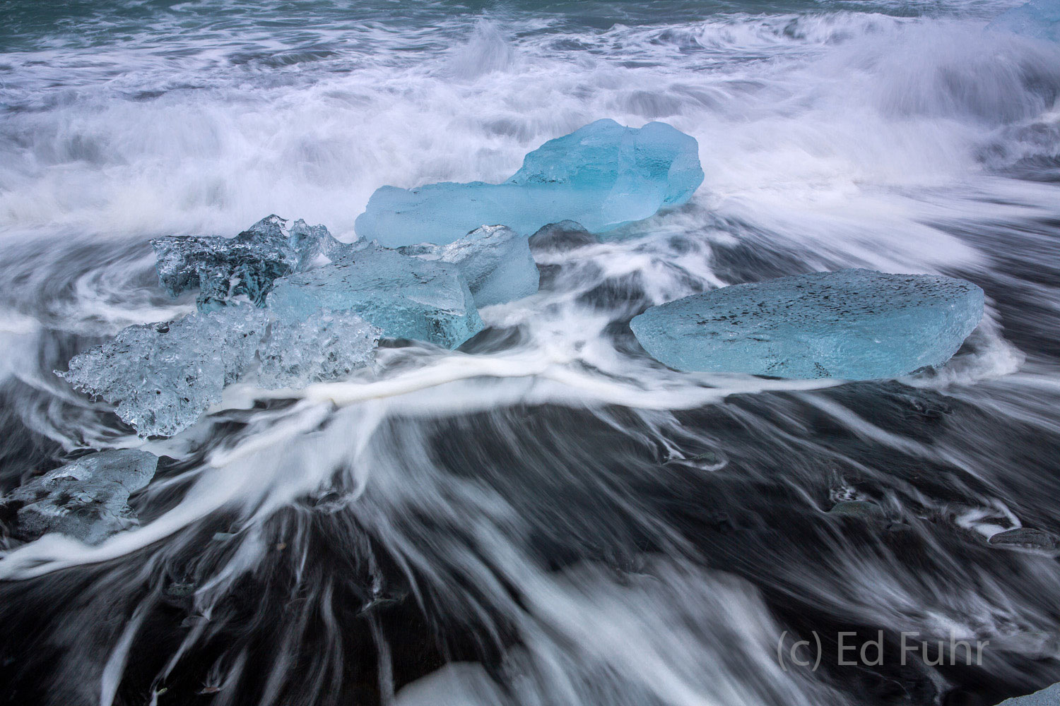 Waves crest and spill over the icy remnant of a disappearing glacier.