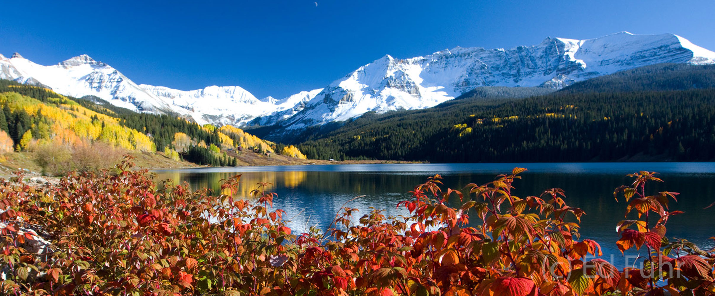 Sheltered from the wind, Trout Lake is surrounded by snowy peaks and a stunning array of yellows and reds&nbsp;