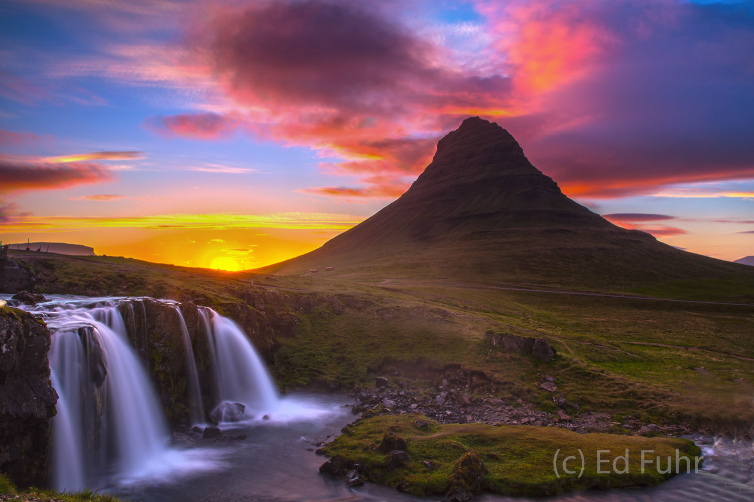 The midnight sun "sets" behind Mt. Kirkjufell only to rise minutes later above the mountains and its waterfall, Kirjufellsfoss...