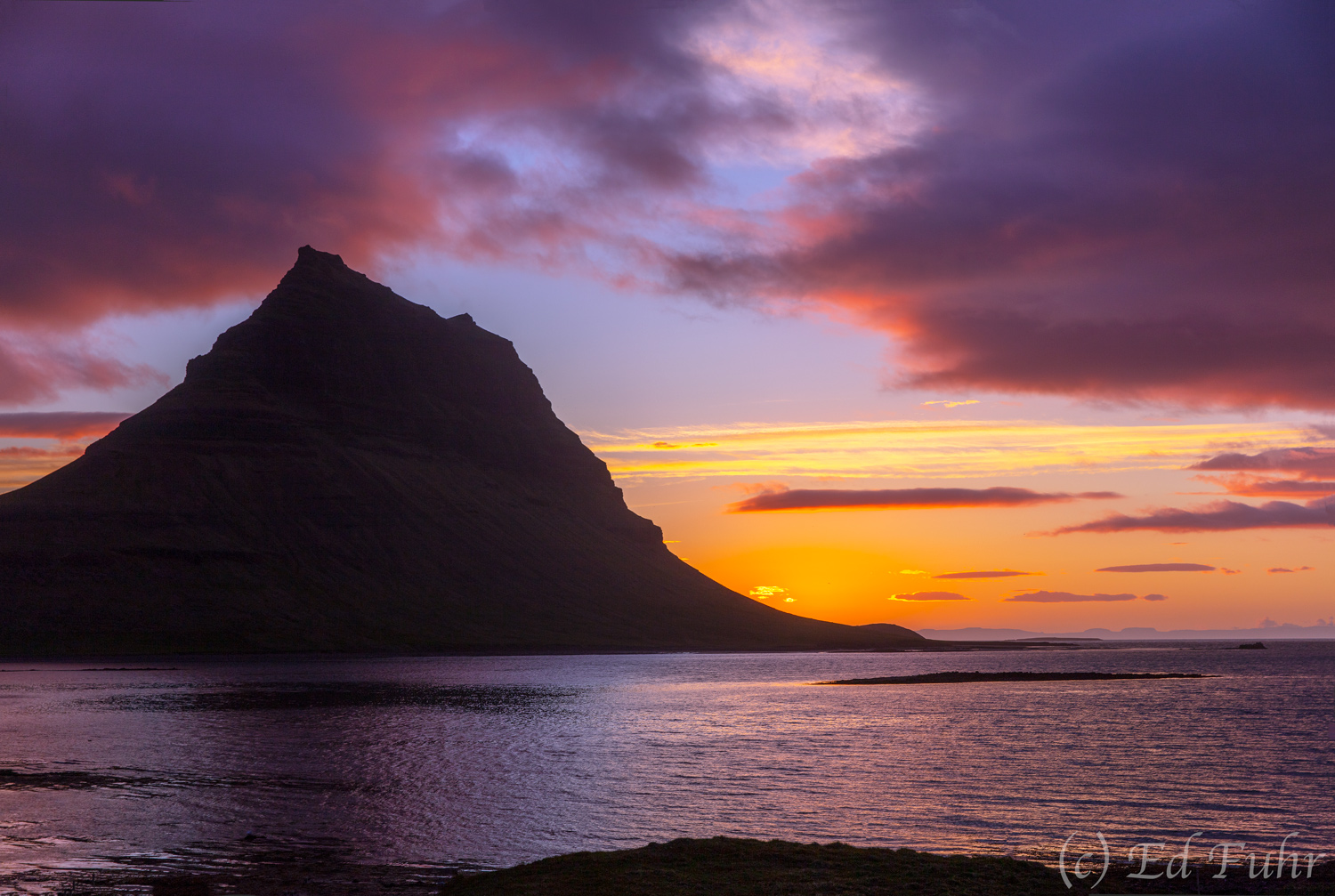 Mt. Kirkjufell at Sunset Rising 1519 feet above the sea, Mt. Kirkjufell stands at midnight above the shallow bay that separates Iceland's Snaefellsness...