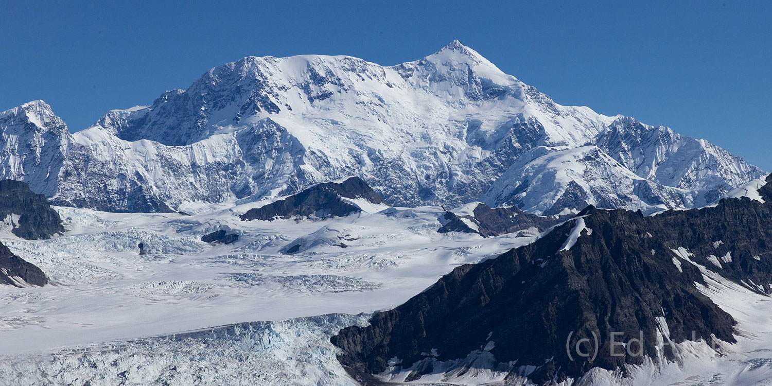 Another of Wrangell-St. Elias' large and remote mountain peaks rises above the volcanic below.