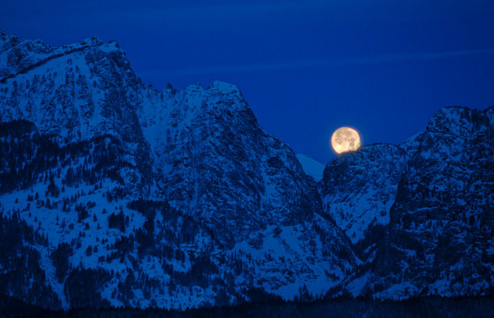 Moments after a lunar eclipse, a full moon sets over the Teton Range.&nbsp;